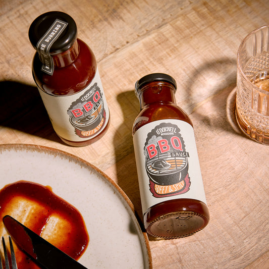 O'Donnell Moonshine BBQ Sauce Sweet & Spicy – zwei Flaschen von oben auf Holzuntergrund mit Teller und Glas, Flatlay-Aufnahme