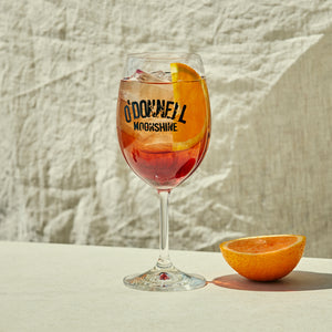 Ein volles Sprtizglas mit einer halben Orange daneben