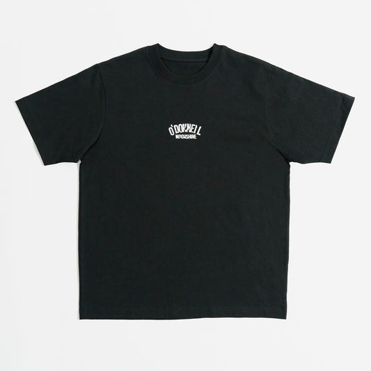 Quadratische Produktansicht für O'Donnell Moonshine: Ein schwarzes T-Shirt mit einem kleinen, weißen Marken-Logoprint im Vintage-Stil auf der Brust, freigestellt vor weißem Hintergrund.