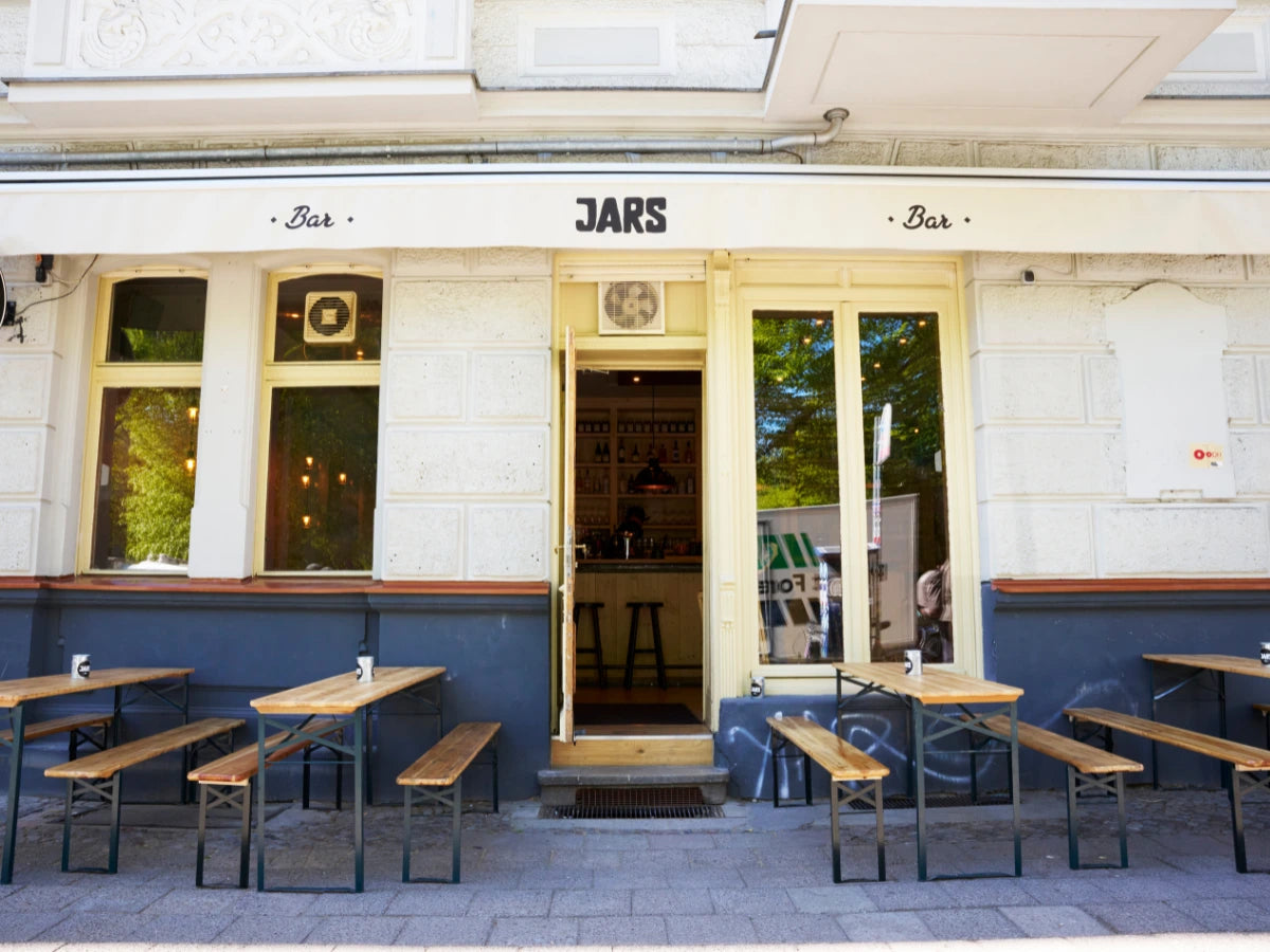 Außenbereich des JARS Bars in Berlin mit Eingang, Bänken und Tischen