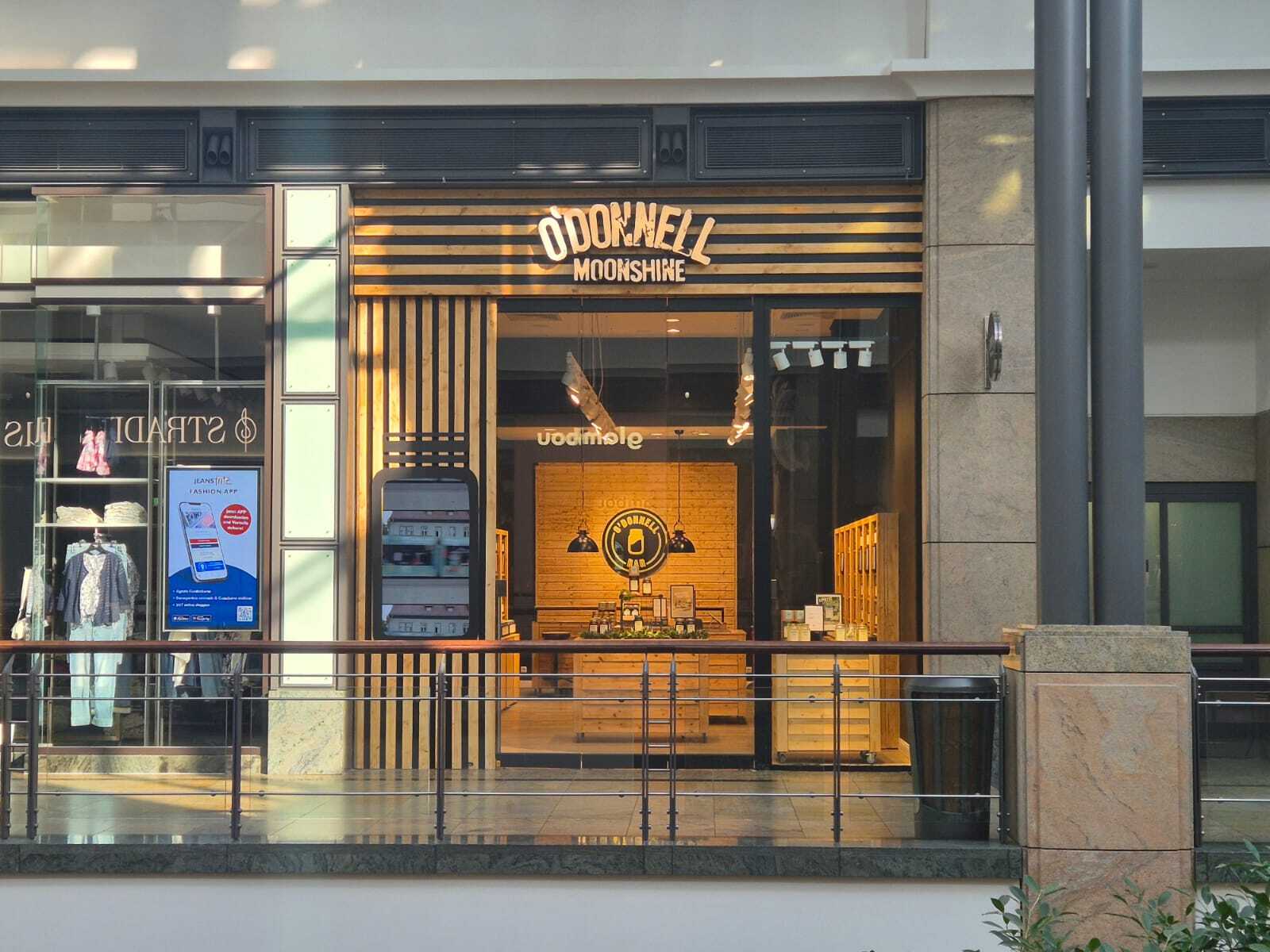O'Donnell Moonshine Ladengeschäft in einem Einkaufszentrum – Außenansicht mit beleuchteter O'Donnell Moonshine-Beschilderung und warmem Holzladendesign