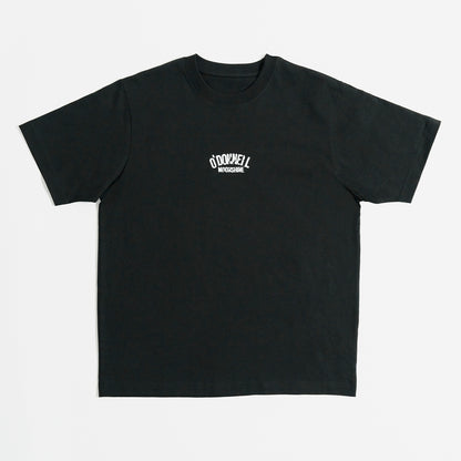 Quadratische Produktansicht für O'Donnell Moonshine: Ein schwarzes T-Shirt mit einem kleinen, weißen Marken-Logoprint im Vintage-Stil auf der Brust, freigestellt vor weißem Hintergrund.