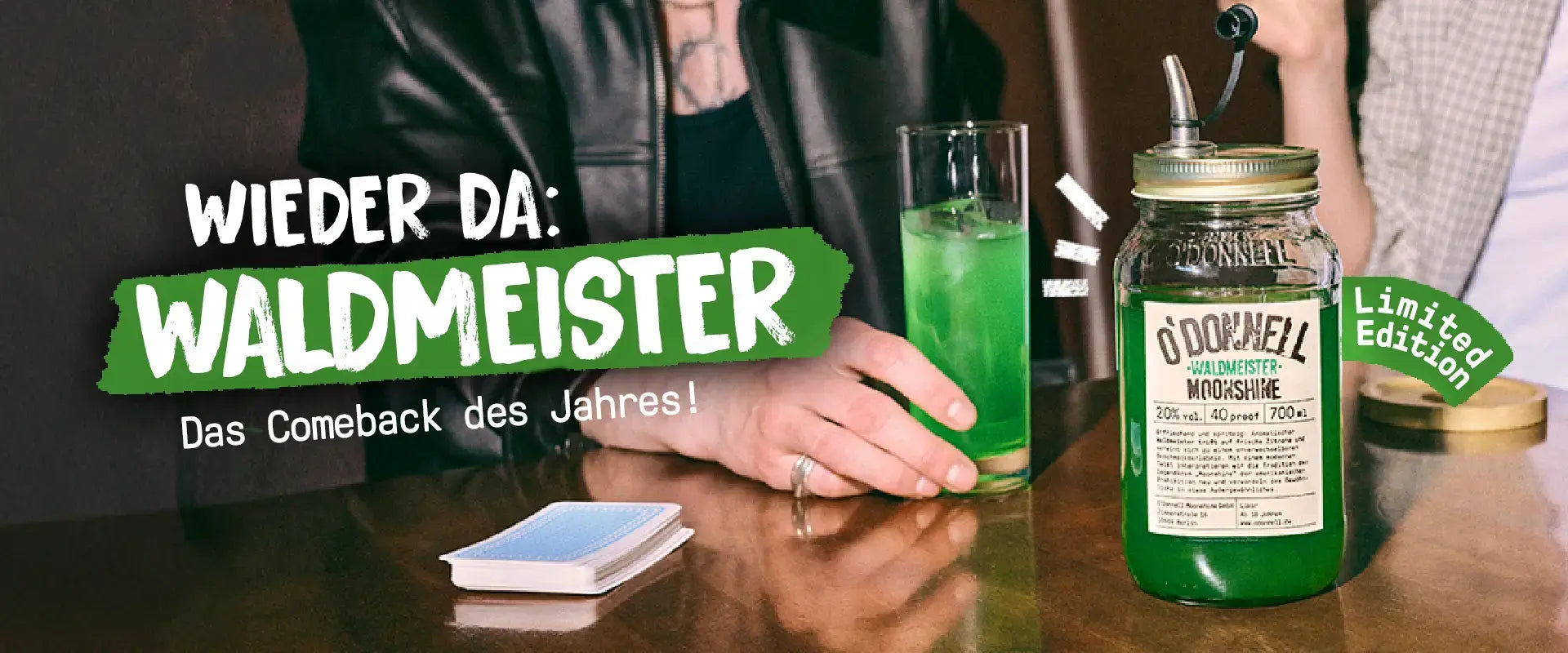 O'Donnell Moonshine Mobile LP Banner für die zurückkehrende Sorte Waldmeister mit 700ml Mason Jar auf einem Kneipentisch.