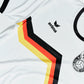 Nahaufnahme des O'Donnell Moonshine WM 2026 Trikots – schwarz-rot-goldener Chevron-Streifen mit erima-Logo und Copa-Wappen auf weißem Stoff