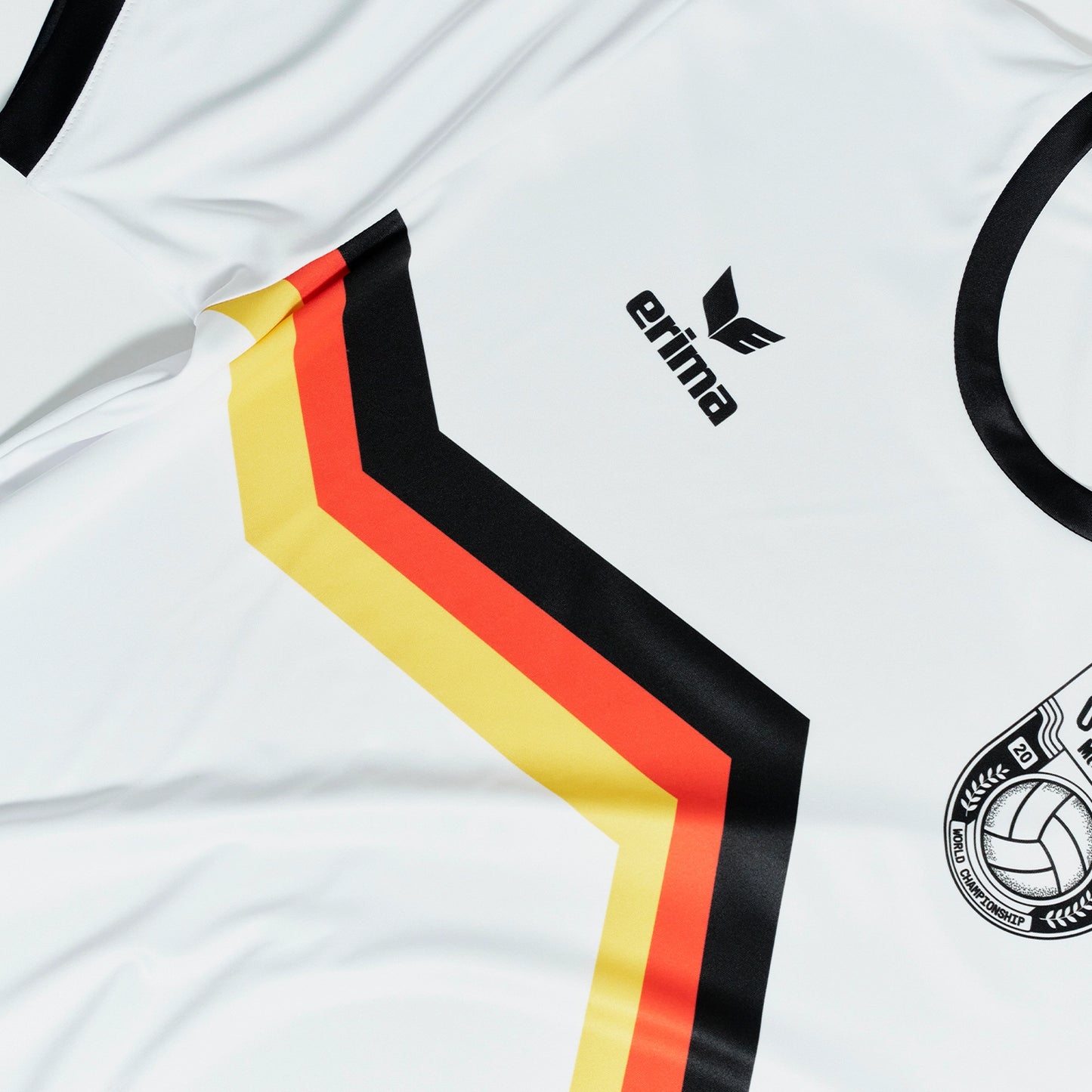 Nahaufnahme des O'Donnell Moonshine WM 2026 Trikots – schwarz-rot-goldener Chevron-Streifen mit erima-Logo und Copa-Wappen auf weißem Stoff