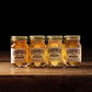 Vier kleine O'Donnell Moonshine Likörflaschen (50ml) der Wintersorten auf rustikalem Holz vor schwarzem Hintergrund.