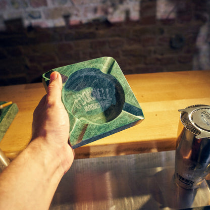 Der O'Donnell Moonshine Aschenbecher hinter der Bar und wird in der Hand gehalten.