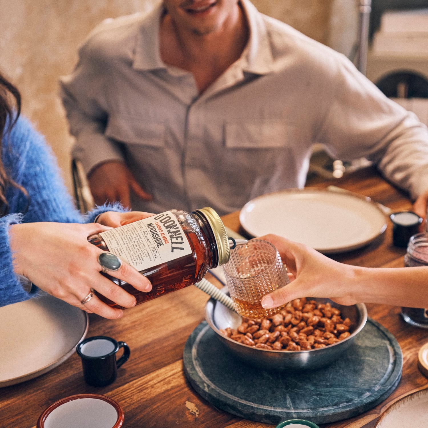 Eine Frau schenkt jemanden ein Schluck O'Donnell Moonshine gebrannte Mandel ein am Esstisch ein.