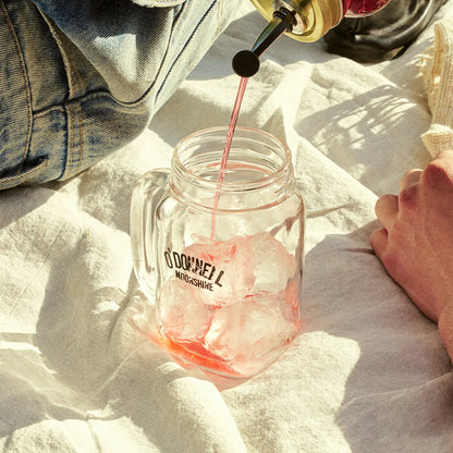 O'Donnell Moonshine Likeur wird in ein Henkelglas mit Eiswürfeln eingegossen – Outdoor-Lifestyle auf Leinentuch, Sonnenlicht