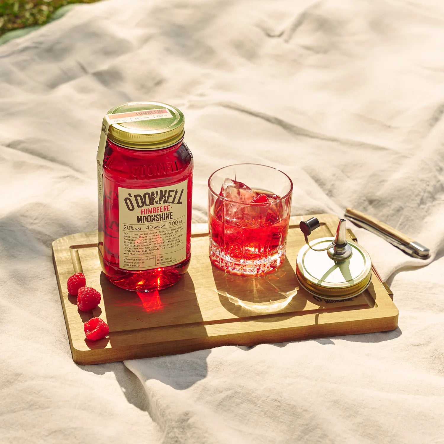 O'Donnell Moonshine Himbeere Flasche und Cocktailglas mit Eis auf Holzbrett mit frischen Himbeeren